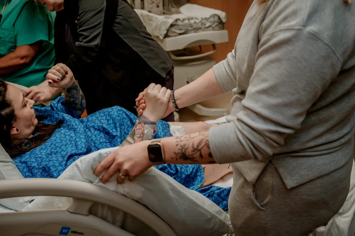 A doula holding a laboring client's hand for support during birth