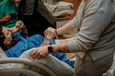 A doula holding a laboring client's hand for support during birth
