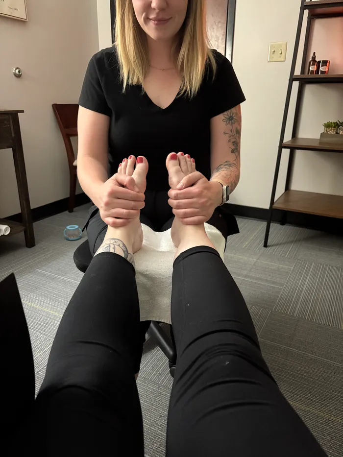 Jessica gently cradling a client's foot during a foot zone session