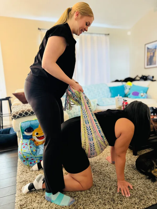 Jessica guiding a client through a rebozo technique during a hands-and-knees labor prep exercise