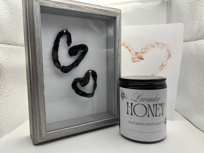 Framed umbilical cord keepsake hearts beside a placenta print art card and a Lavender Honey candle